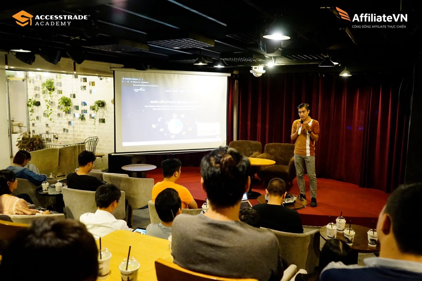 Hoàng Thanh Long cầm micro chia sẻ tại buổi offline Affiliate